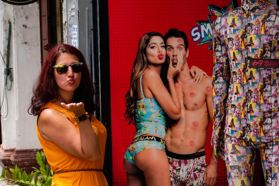 A woman standing next to a poster. Poster advertising underwear. The photo was taken in the old town of Phuket