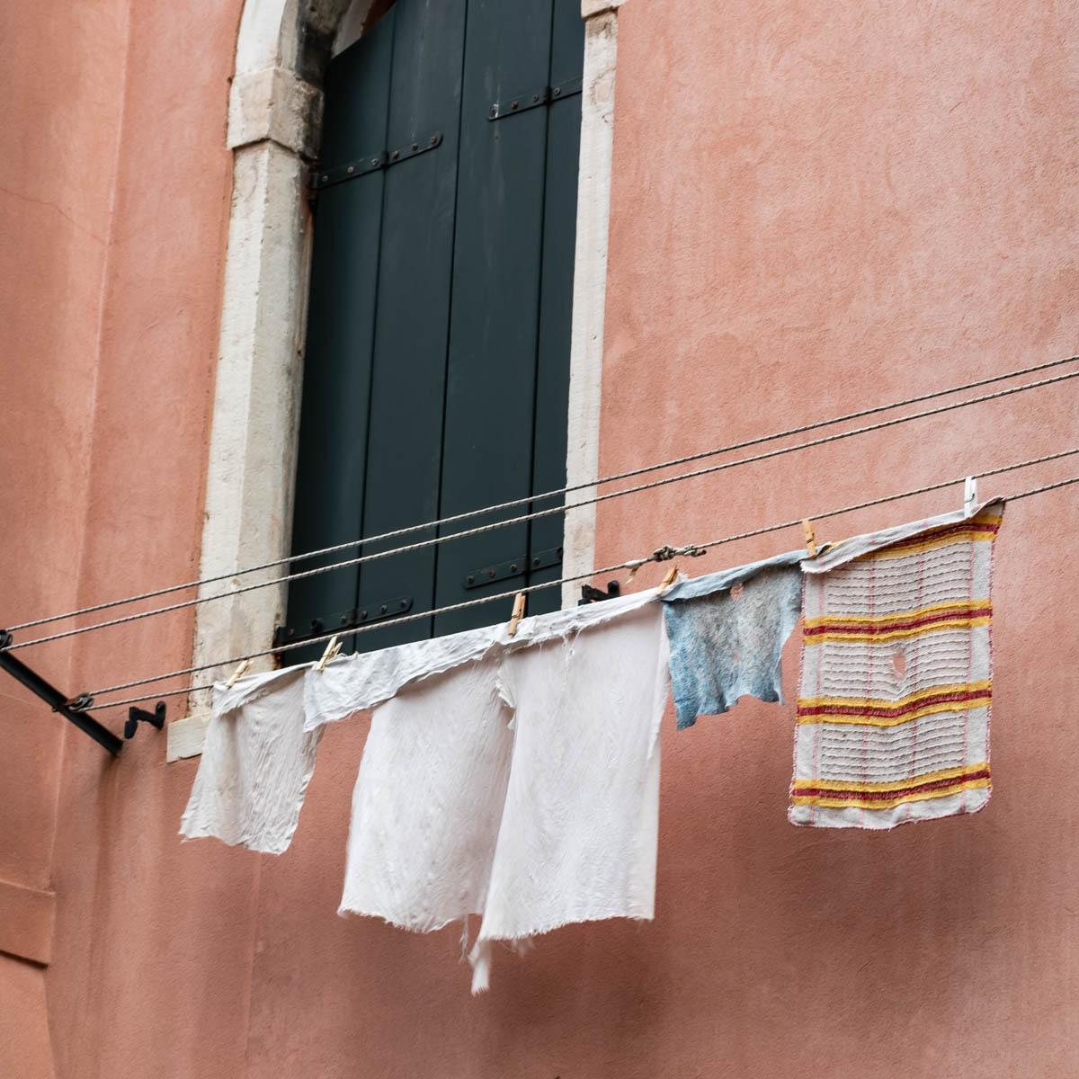 Clothes hanging behind a traditional window in Venice, Italy — what still remains of the everyday life of the Venetian people