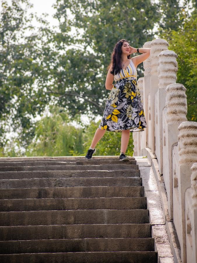 A beautiful Persian woman in a colorful dress standing on one of the attractive stone bridges in Beijing Summer Garden