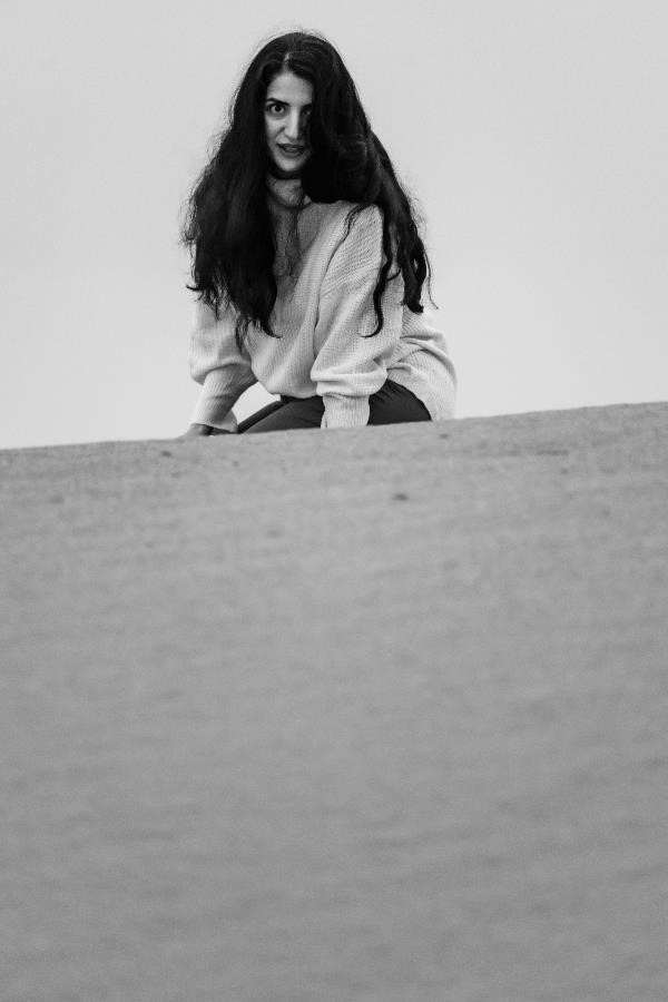 Portrait of a woman sitting on a sand hill in the central desert of Iran