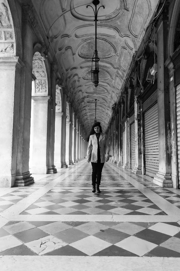 A woman in classical dress walking down one of the corridors around St. Mark's Square in Venice